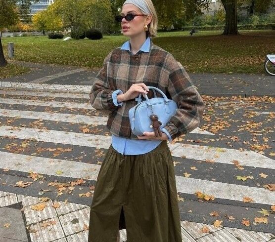 Person i lager-på-lager-outfit med skjorta, rutig tröja och kjol
