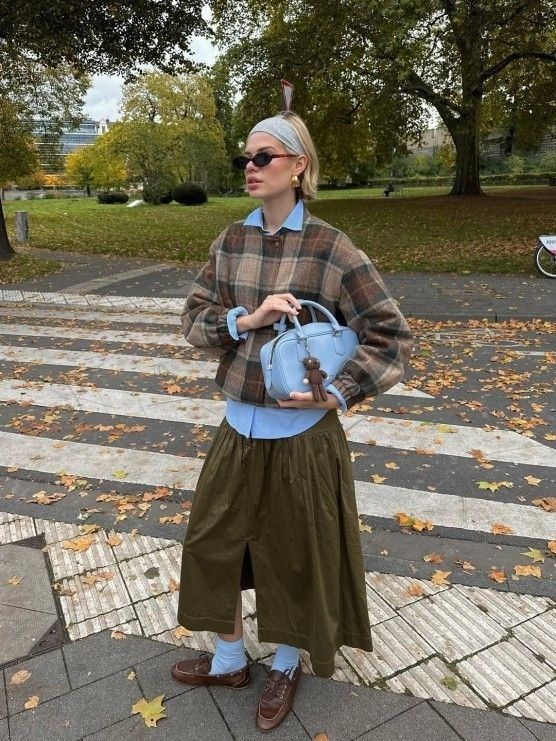 Person i lager-på-lager-outfit med skjorta, rutig tröja och kjol